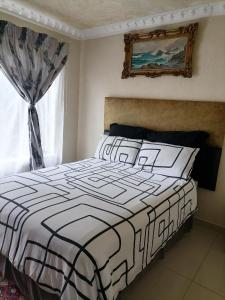 a bedroom with a black and white bed and a window at Imvumbu Guest House in Nelspruit
