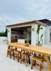 een houten tafel en stoelen op een patio met een keuken bij Gypsea Rest Villa in Nusa Lembongan