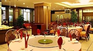 een eetkamer met tafels en stoelen met rode decoraties bij Longda Ruiji Business Hotel Harbin in Harbin