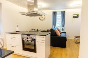 a kitchen with a stove top oven next to a living room at Jasminkas Host 3 - Stadtwohnung mit Küche & gratis Parkplatz in St. Gallen +8 photos