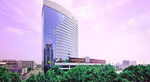 a tall building in a city with trees in front of it at Jiaxing Sunshine Hotel in Jiaxing
