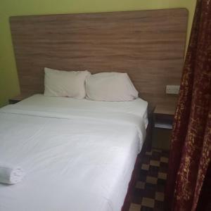 a bed in a hotel room with white sheets and pillows at Venguest Homes & Accomodation in Naivasha