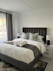 a bedroom with a large bed with white sheets and pillows at 2 Bedroom Condo in Sunninghill Sandton in Sandton