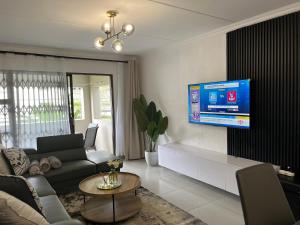 a living room with a couch and a tv on a wall at 2 Bedroom Condo in Sunninghill Sandton in Sandton