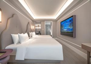 een slaapkamer met een groot wit bed en een flatscreen-tv bij Mercure Anyang Downtown in Anyang