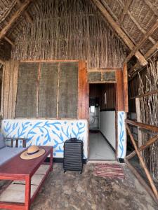 ein Zimmer mit einem Sofa und einem Tisch in einer Strohhütte in der Unterkunft Kibwana Beach Bungalows & Diving in Matemwe