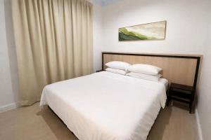 a bedroom with a large white bed with white pillows at Kanza Beach Inn in Marang