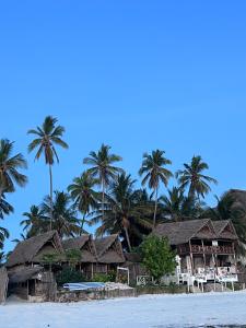ein Resort am Strand mit Palmen in der Unterkunft Kibwana Beach Bungalows & Diving in Matemwe
