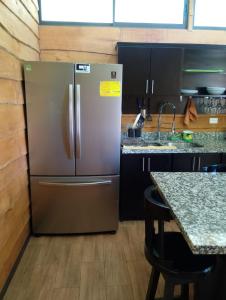 a stainless steel refrigerator in a kitchen with a table at Domi Hostel in Dominical