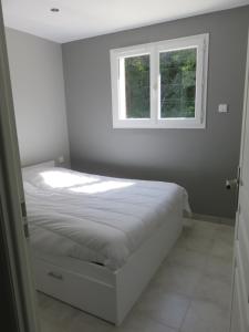een witte slaapkamer met een bed en een raam bij La petite maison in Malataverne