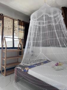 ein Bett mit einem Netzhimmel in einem Zimmer in der Unterkunft Kibwana Beach Bungalows & Diving in Matemwe