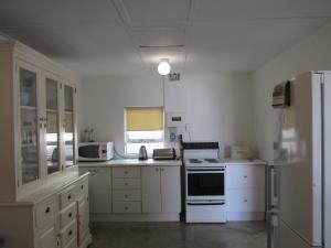 uma cozinha com armários brancos e um frigorífico branco em Point Village Accommodation - Point Road 20 em Mossel Bay