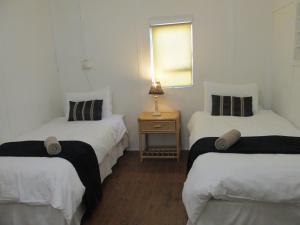 モッセル・ベイにあるPoint Village Accommodation - Point Road 20のベッド2台、テーブル(ランプ付)が備わる客室です。