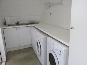 uma cozinha branca com um lavatório e uma máquina de lavar roupa em Point Village Accommodation - Point Road 20 em Mossel Bay