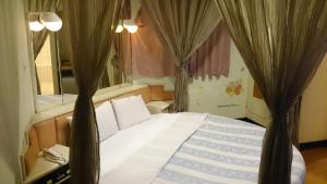 Schlafzimmer mit einem Bett mit Vorhängen in der Unterkunft Rido Hotel in Taichung