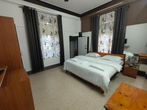 a bedroom with a large bed and two windows at Hotel ODC Residency in Jowai +29 photos