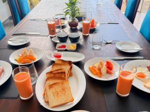 a table with plates of breakfast foods and glasses of orange juice at Florain Otium Talpe - 3 Bedroom Oceanfront Villa in Unawatuna