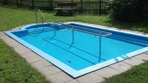 an empty swimming pool with blue water in a yard at Gottschlich Apartment Schmallenberg in Schmallenberg