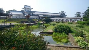 a building with a pond in front of a garden at Hotel Crown Hills Kanazawa in Kanazawa