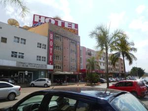 a parking lot with cars parked in front of a hotel at Atlas Hotel Residence in Taguatinga