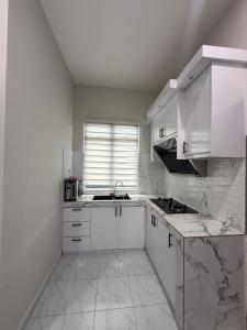 een witte keuken met een wastafel en een raam bij Eyqa Homestay Pasir Mas in Pasir Mas
