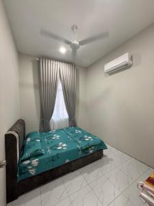 een slaapkamer met een bed met een groen dekbed en een raam bij Eyqa Homestay Pasir Mas in Pasir Mas