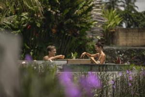 due uomini seduti in una vasca da bagno in un giardino di Beehouse Dijiwa Ubud ad Ubud Altre 67 foto