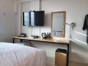 een slaapkamer met een bureau met een spiegel en een bed bij Haemil Stay in Daegu