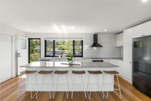 een keuken met een groot wit eiland met barkrukken bij The Grevilleas in Woombah