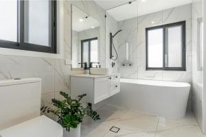 een witte badkamer met een bad, een wastafel en een tubermott bij The Grevilleas in Woombah +3 foto's