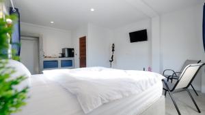 a white bedroom with a white bed and two chairs at Three Monkeys Mae Nam beach in Mae Nam