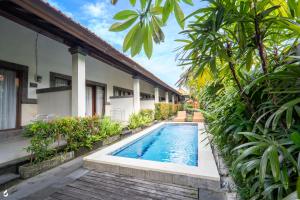 - une piscine en face d'une maison ornée de plantes dans l'établissement Ayu Guest House 2, à Canggu