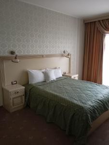 ein Schlafzimmer mit einem Bett mit einer grünen Bettdecke in der Unterkunft Hotel Majestic City Center in Iaşi