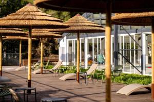 eine Gruppe von Tischen und Stühlen mit Sonnenschirmen in der Unterkunft C Hotel Neve Ilan in Neve Ilan