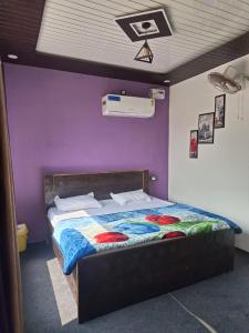 a bedroom with a bed with a purple wall at Gorakhnath Guest House in Gorakhpur
