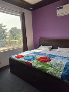 a bed in a room with a purple wall and a window at Gorakhnath Guest House in Gorakhpur