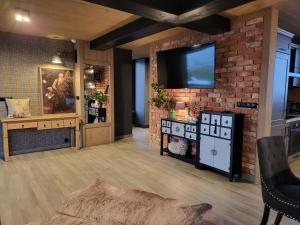 ein Wohnzimmer mit einer Ziegelwand und einem TV in der Unterkunft Białczańskie Bacówki 2, 4sypialnie in Białka Tatrzańska