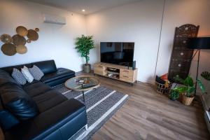 un salon avec un canapé en cuir noir et une télévision dans l'établissement 204 - Luxury Obsidian Condo - Elegance & Pool, à Baie-Saint-Paul