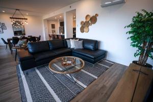 un salon avec un canapé noir et une table dans l'établissement 204 - Luxury Obsidian Condo - Elegance & Pool, à Baie-Saint-Paul