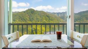 een tafel met een boek en een drankje op een balkon bij Gapyeong Elin Pension in Gapyeong