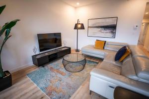een woonkamer met een bank en een flatscreen-tv bij 205 - Modern Suite - Pool and River View in Baie-Saint-Paul