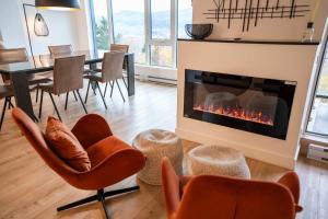 een woonkamer met stoelen en een open haard bij 205 - Modern Suite - Pool and River View in Baie-Saint-Paul +57 foto's