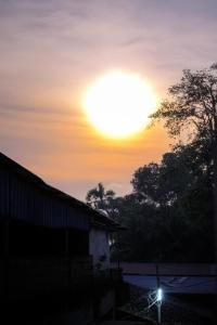 een zonsondergang boven een schuur met de zon aan de hemel bij Aisiri Guest House in Gokarna