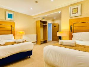 een hotelkamer met twee bedden en twee lampen bij Crown Hotel - Stone, Near Stoke-On-Trent by OYO in Stone +41 foto's
