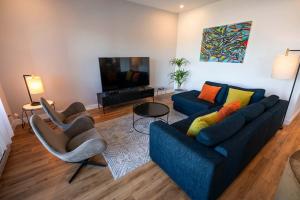 een woonkamer met een bank, stoelen en een televisie bij 209 - Luxury Condo - Pool & River View in Baie-Saint-Paul