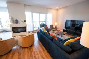 een woonkamer met een blauwe bank en een flatscreen-tv bij 209 - Luxury Condo - Pool & River View in Baie-Saint-Paul