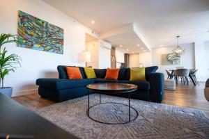 een woonkamer met een blauwe bank en een tafel bij 209 - Luxury Condo - Pool & River View in Baie-Saint-Paul +49 foto's