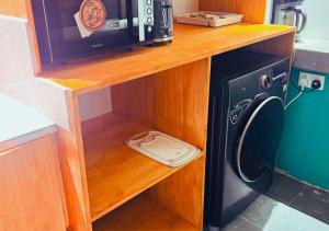 a microwave sitting on a wooden shelf next to a washing machine at Kandoo Cozy Family Room in Huraa