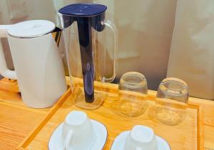 a blender and three cups on a wooden table at Kandoo Cozy Family Room in Huraa