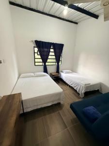 a bedroom with two beds and a blue couch at Villa Esther - Finca campestre en Mesitas del Colegio in El Colegio +9 photos